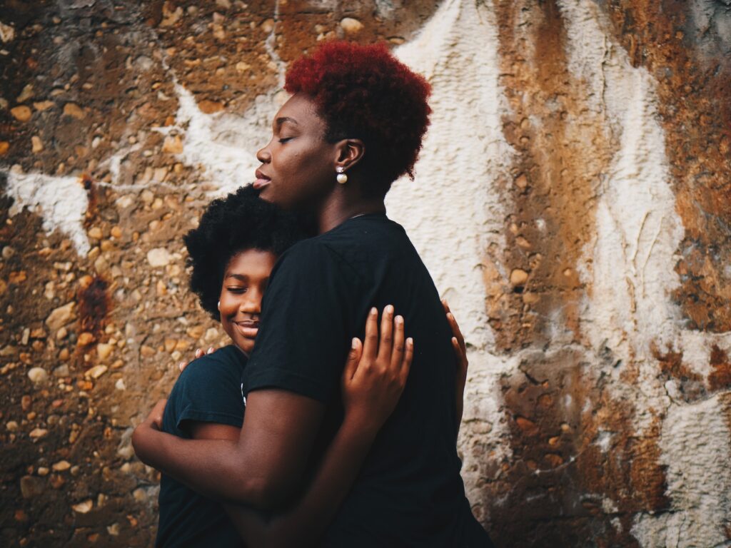 two black women hugging each other compassionately